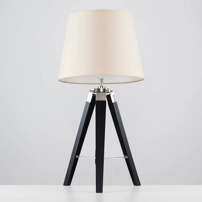 Table lamp with a white shade and black tripod base on a light gray background