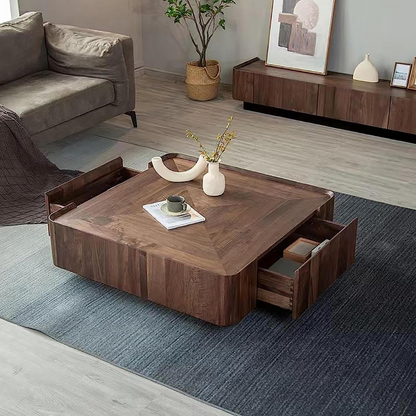 Modern walnut square coffee table with sculpted top in a living room setting, with draws open.