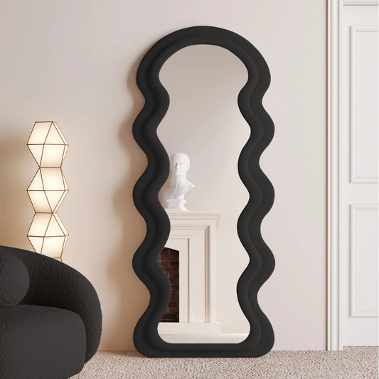 Black wavy mirror in a room with a lamp and chair.