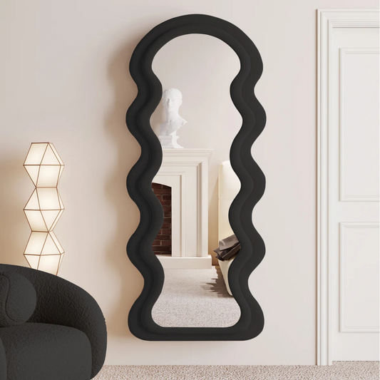 Wavy black mirror in a room with a lamp and sofa.