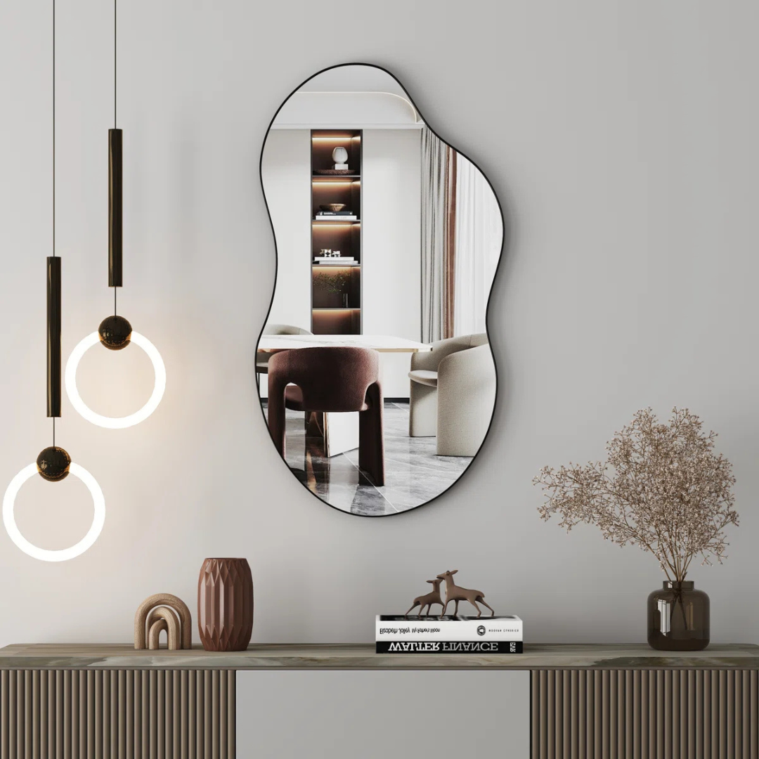 Modern wall mirror on a gray wall with decorative items below.