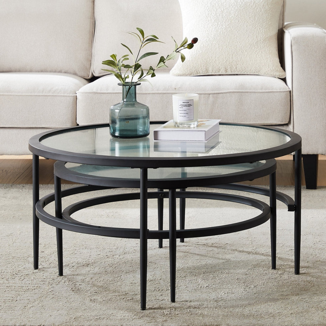 Round glass coffee table with black metal frame in a living room setting.