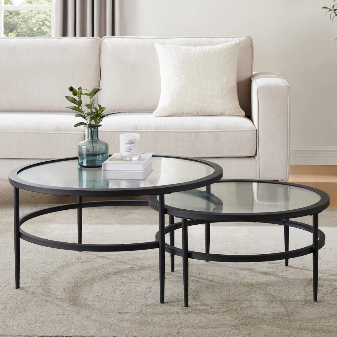 Two round glass coffee tables with black metal frames in a living room setting.