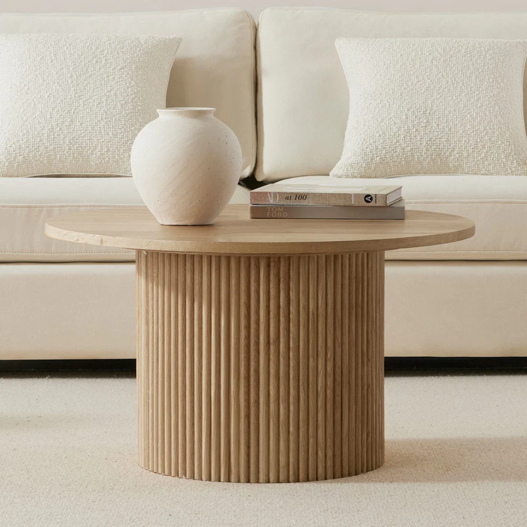 Wooden side table with a vase and books against a beige sofa.