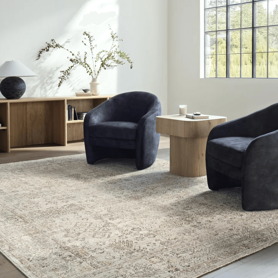 Modern living room with dark blue armchairs, a light wood coffee table, and decorative elements.