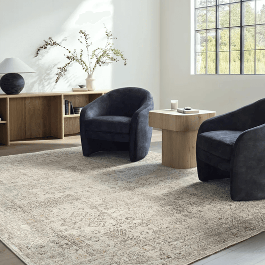 Modern living room with dark blue armchairs, a light wood coffee table, and decorative elements.