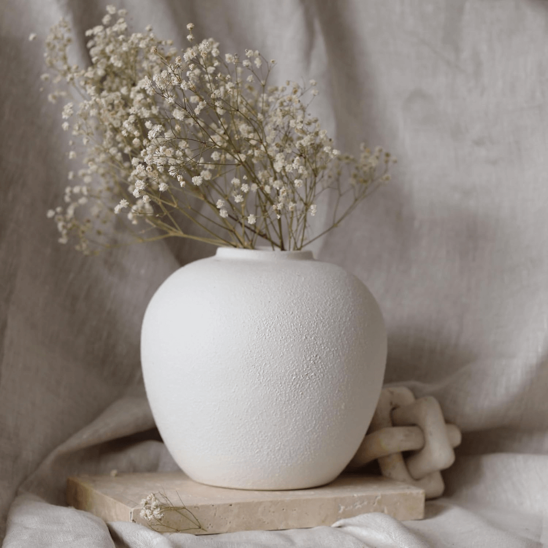 White textured vase with dried flowers on a neutral background