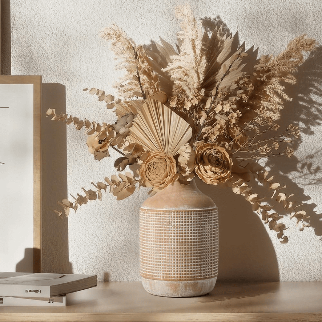 Decorative vase with dried flowers on a wooden surface