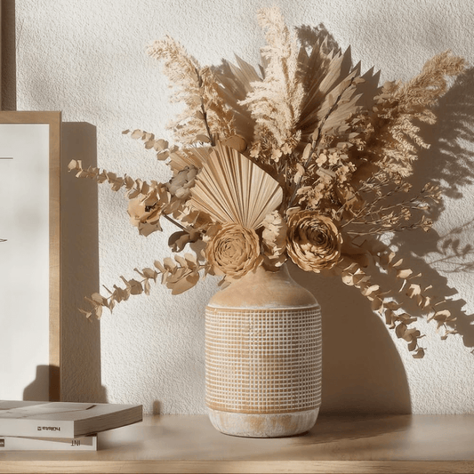 Decorative vase with dried flowers on a wooden surface