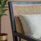 Close-up of a chair with woven backrest and gray cushion, blurred background