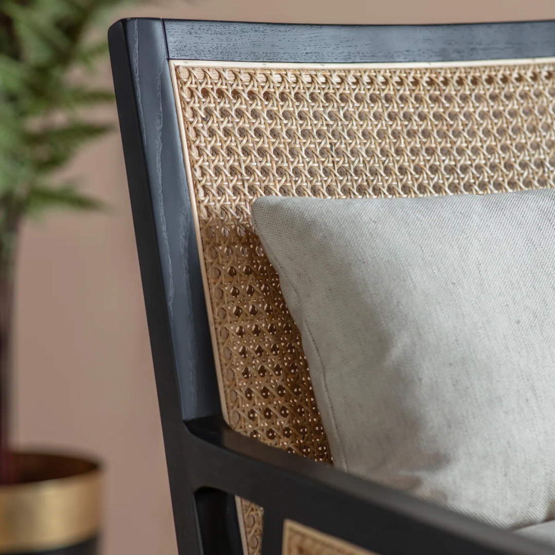 Close-up of a chair with woven backrest and gray cushion, blurred background