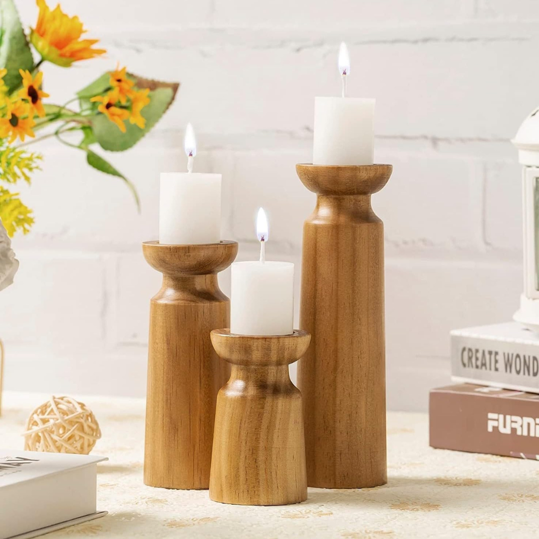 Three wooden candle holders with candles on a surface, with a blurred background.