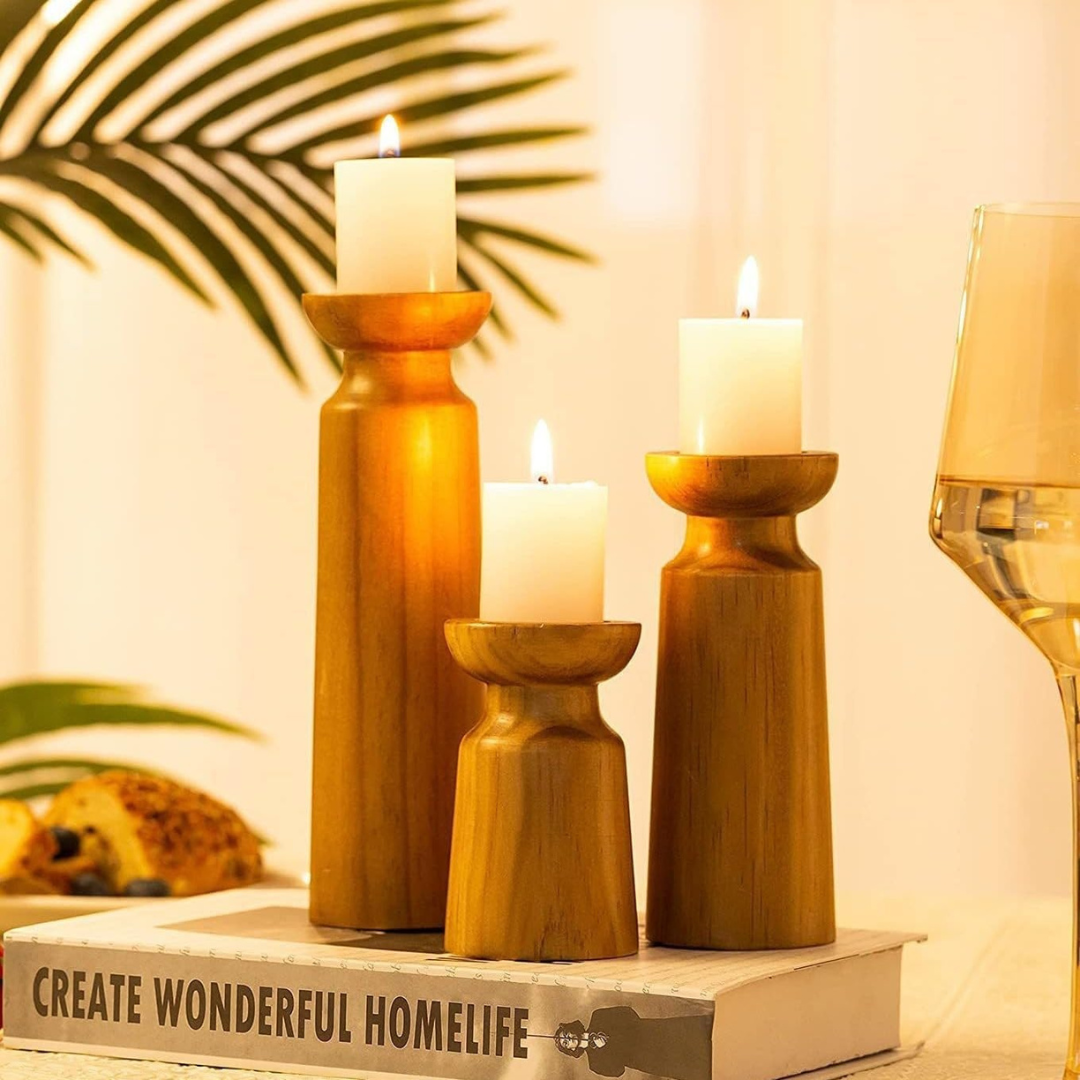 Three wooden candle holders with candles on a book titled 'Create Wonderful Homelife'.