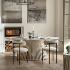 Modern dining room with a round table and chairs, fireplace, and abstract art.