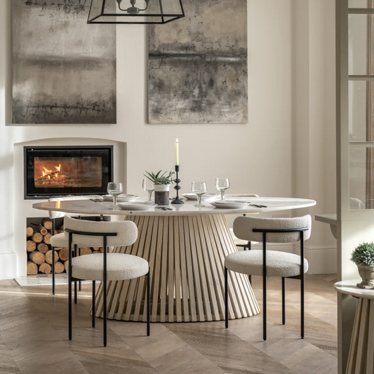 Modern dining room with a round table and chairs, fireplace, and abstract art.