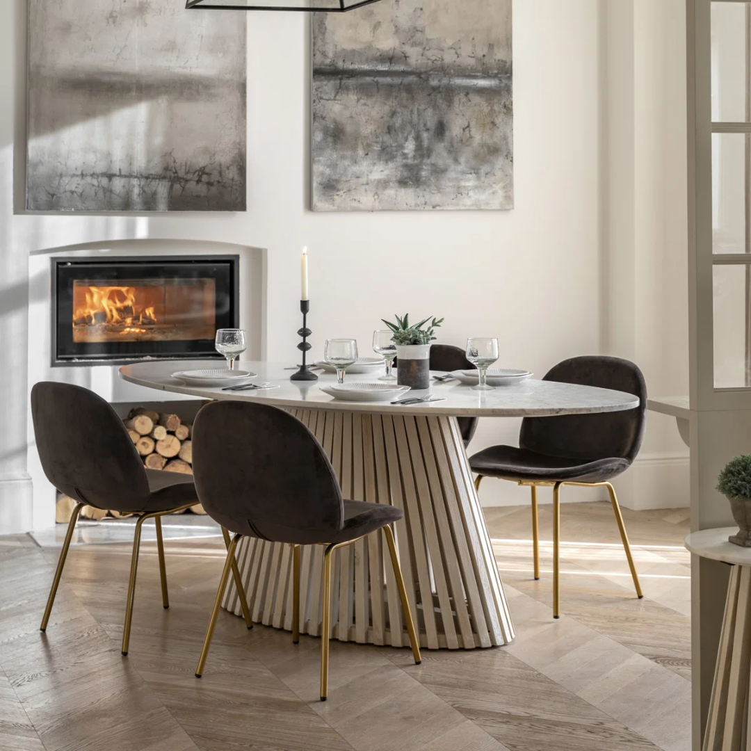 Modern dining room with a marble table and black chairs in front of a fireplace.