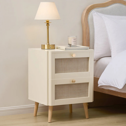 Beige nightstand with lamp and candle next to a bed