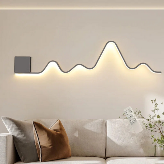 Modern wall-mounted light fixture on a neutral wall above a sofa with decorative pillows.