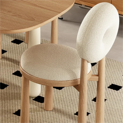 white boucle dining chair with curved back and soft seat, close up of boucle fabric. Chair is sat around a dining table.