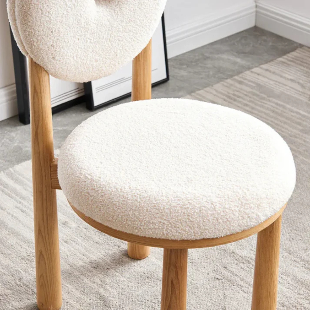 white boucle dining chair with curved back and soft seat, close up of boucle with a grey background.